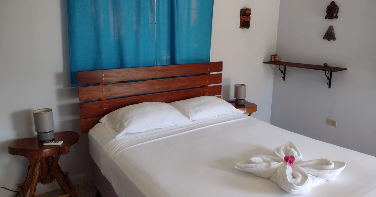 A made bed with a folded towel flower in a private en-suite room