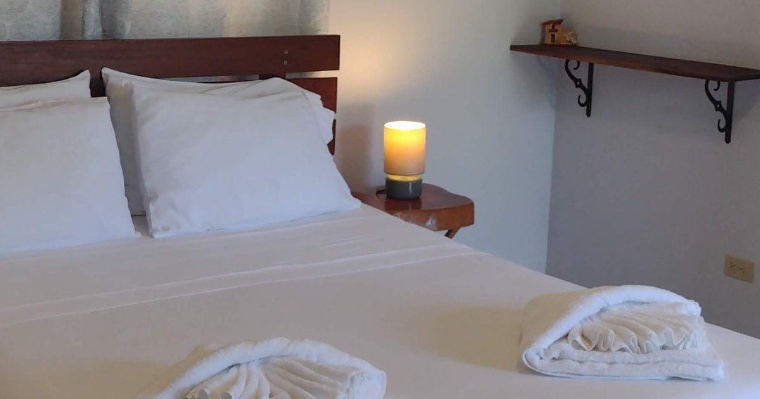 A freshly made bed in one of the guesthouse rooms