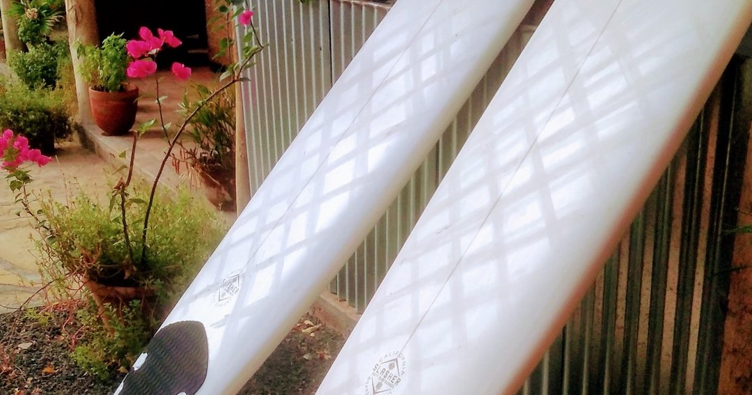 Two white surfboards leaning against a wall outdoors